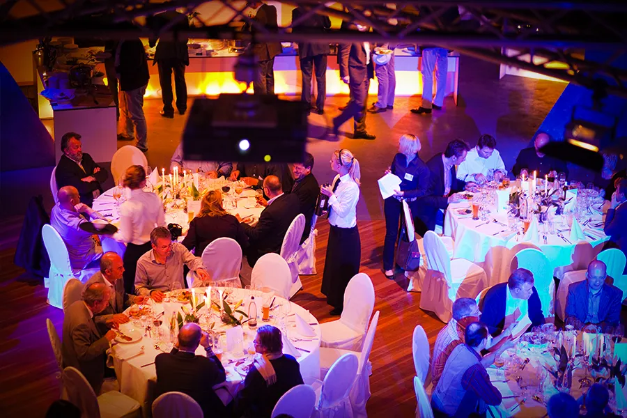 Gala Dinner im OKTOGON auf Zollverein in Essen mit Gästen an festlich gedeckten Rundtischen und stimmungsvoller Beleuchtung