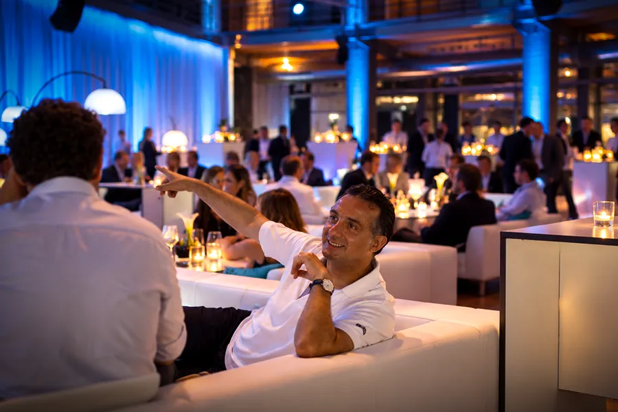 Gäste im Gespräch auf weißen Lounge-Sofas bei einem Get-together im OKTOGON auf Zollverein in Essen mit stimmungsvoller Eventbeleuchtung